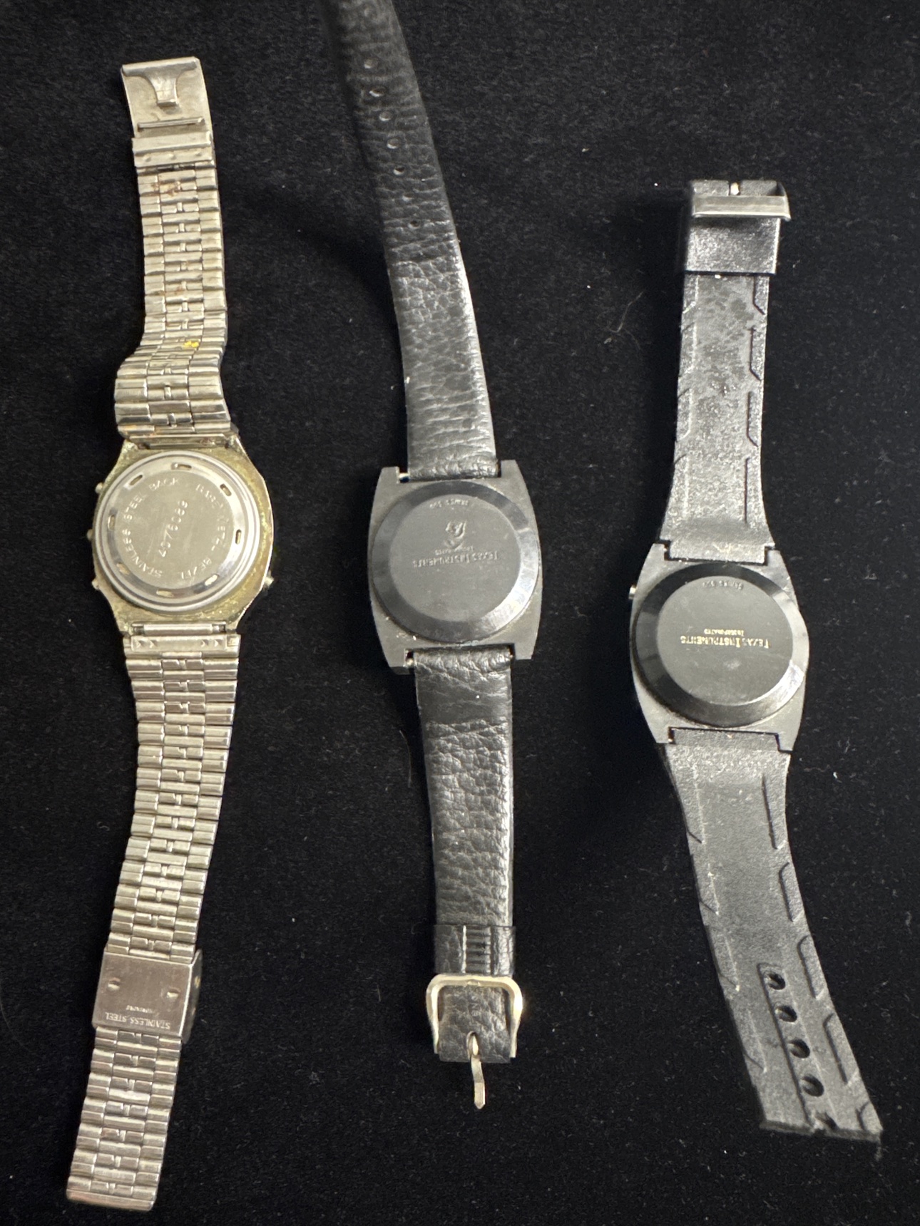Backs of all three vintage digital watches in the parts and repair lot
